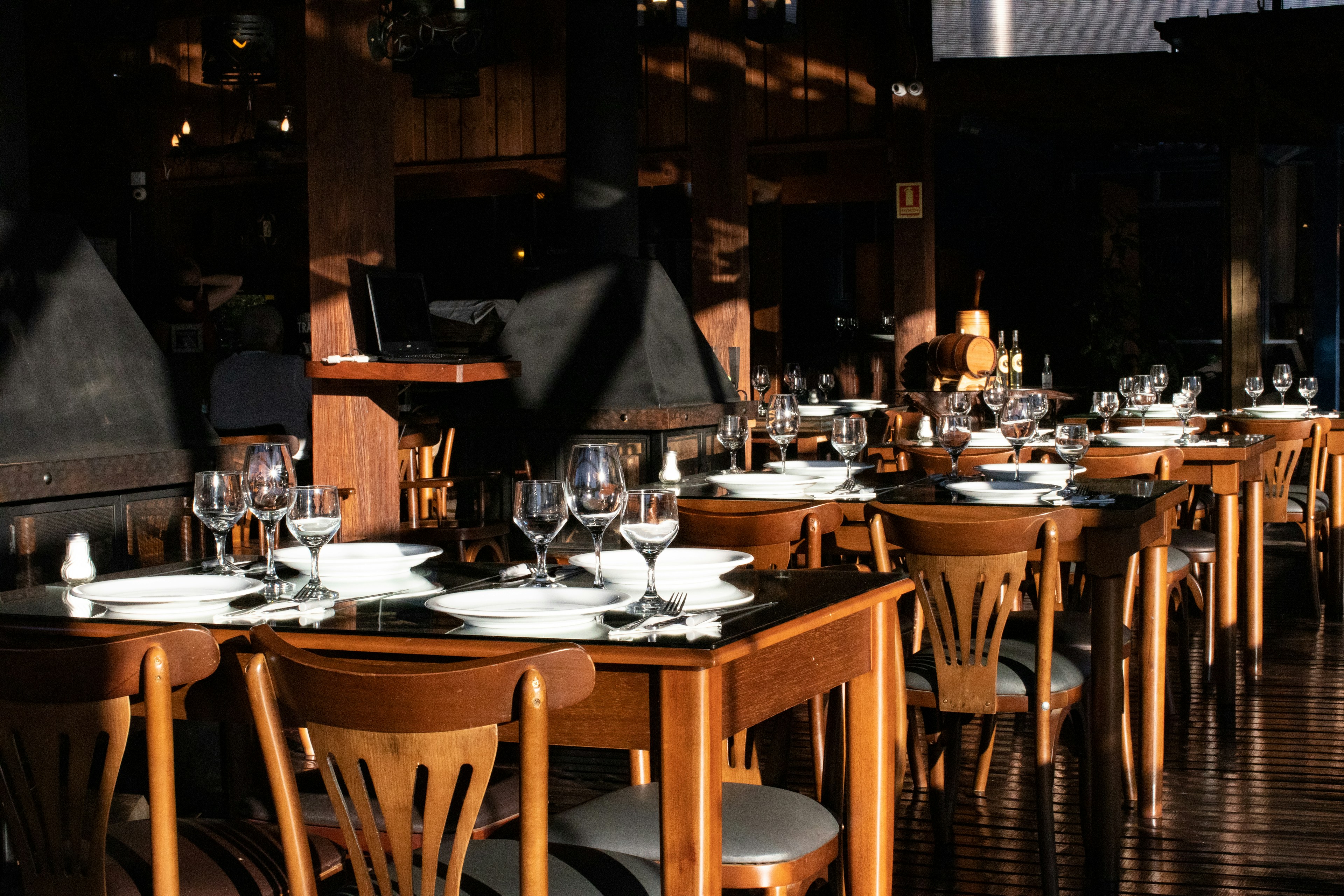 Mese din lemn, pahare și lumină caldă într-un restaurant